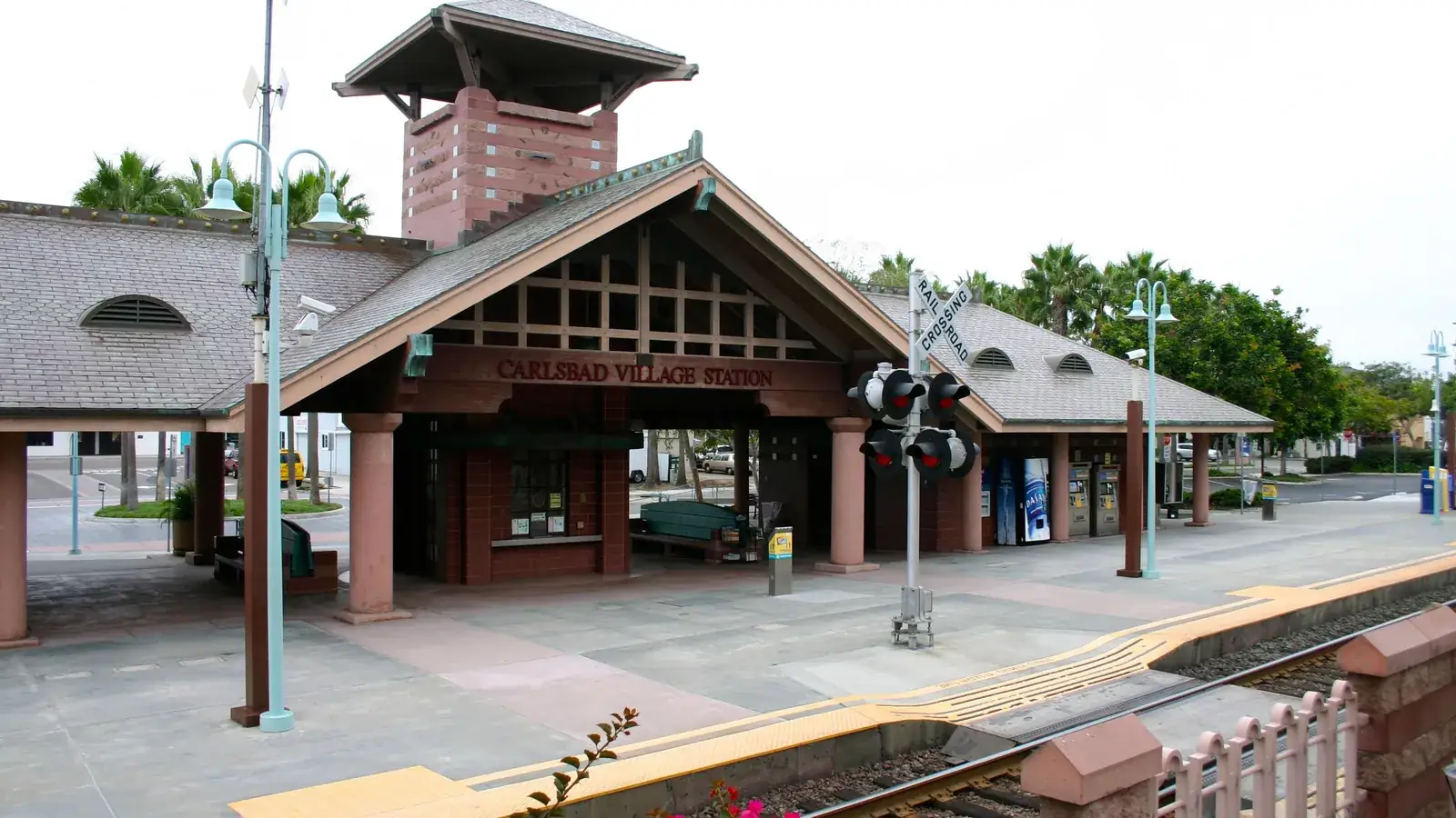 The Carlsbad Village Coaster station, a low building with a brown roof beside the tracks.