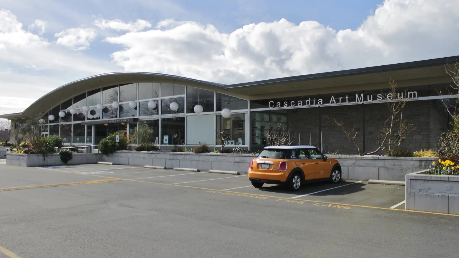 The glass and wood exterior of Cascadia Art Museum in Edmonds, with a sign by the entrance.