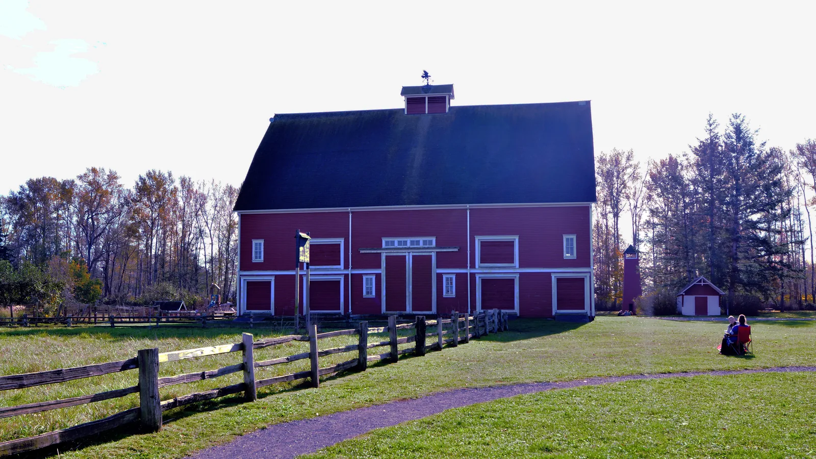 The red barn with a dark gambrel roof at Hovander Homestead Park, with grass in front and trees behind.