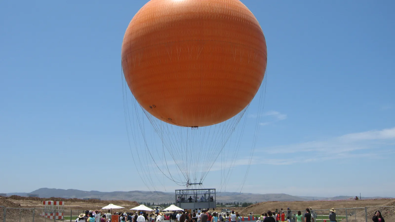 The orange Great Park Balloon on its lawn, with the carousel and visitors below.